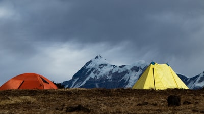 橙棕色草地上帐篷附近冰雪覆盖山白天

